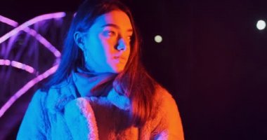 Geceleri kırmızı ve mavi neon ışıklı güzel esmer kadın. Makyajlı ve renkli küpeli manken kız.