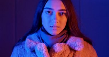 Genç bir kadın, neon ışıklı arka planda sanal gerçeklik gözlüğü takıyor. VR gözlüklü çekici kız.