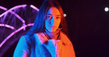 Geceleri kırmızı ve mavi neon ışıklı güzel esmer kadın. Makyajlı ve renkli küpeli manken kız.