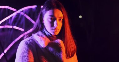 Geceleri kırmızı ve mavi neon ışıklı güzel esmer kadın. Makyajlı ve renkli küpeli manken kız.