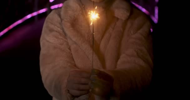 Étincelles dans les mains de la jeune femme. Sparks disperse dans différentes directions à l'arrière-plan néon lumières — Video