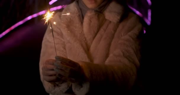 Sparklers in handen van jonge vrouwen. Vonken verstrooit in verschillende richtingen op neon lichten achtergrond — Stockvideo