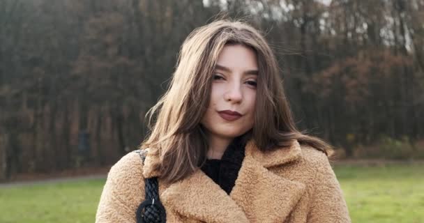 Retrato de jovem fêmea atraente que sorrindo e olhando para a câmera no gramado verde. Mulher alegremente bonita. Fechar — Vídeo de Stock