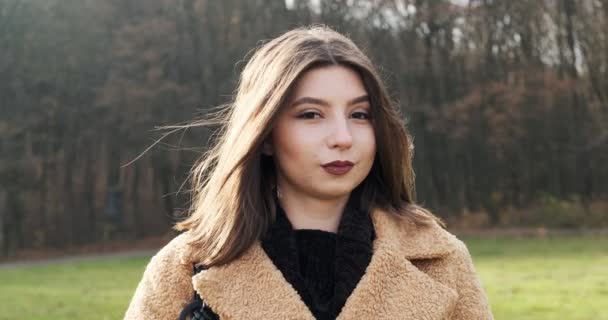 Retrato de jovem fêmea atraente que sorrindo e olhando para a câmera no gramado verde. Mulher alegremente bonita. Fechar — Vídeo de Stock