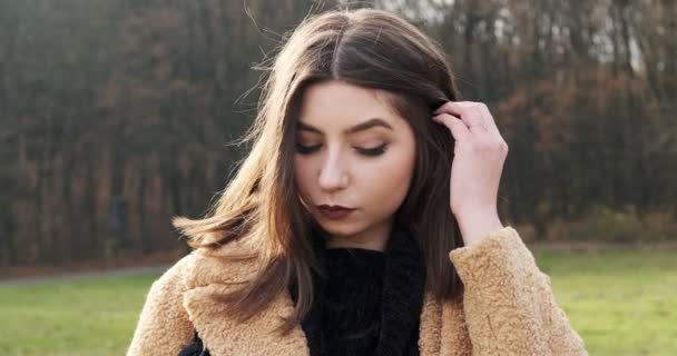 Ritratto di giovane femmina attraente che sorride e guarda la macchina fotografica sul prato verde. Una donna allegramente carina. Da vicino. — Video Stock