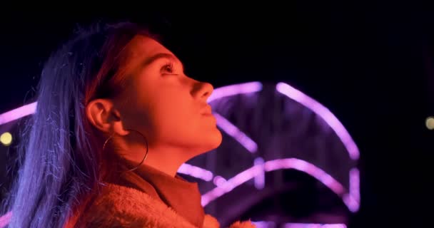 Hübsche brünette Frau in rotem und blauem Neonlicht in der Nacht. Modelmädchen mit Make-up und Kreis-Ohrringen in farbenfroher Beleuchtung — Stockvideo