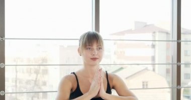 Güzel genç bir kadın büyük pencereli odada yoga egzersizi yapıyor. Vücuduyla çalışan çekici bir kadın. Rahatlama kavramı