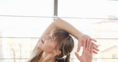 Güzel genç bir kadın büyük pencereli odada yoga egzersizi yapıyor. Vücuduyla çalışan çekici bir kadın. Rahatlama kavramı