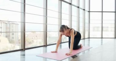 Güzel genç bir kadın büyük pencereli odada yoga egzersizi yapıyor. Vücuduyla çalışan çekici bir kadın. Rahatlama kavramı