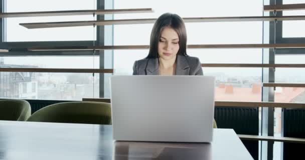 En bekymret kvinne som jobber med en bærbar datamaskin og ser bort og tenker på å løse problemer på jobben. Alvorlig attraktiv kvinne som jobber med notatbok – stockvideo
