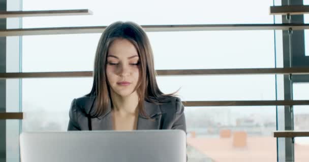 Concerned woman working on laptop computer and looking away thinking solving problem at office. Serious attractive female working with notebook — ストック動画