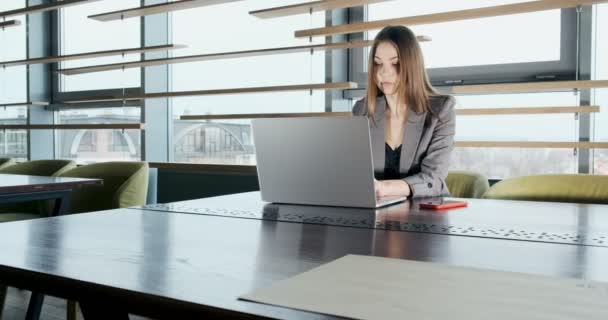 Mujer preocupada trabajando en el ordenador portátil y mirando hacia otro lado pensando en resolver el problema en la oficina. Femenina atractiva seria trabajando con cuaderno — Vídeos de Stock