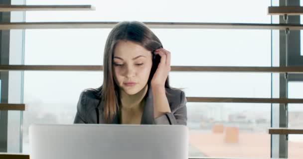 Mulher preocupada trabalhando no computador portátil e olhando para longe pensando resolver problema no escritório. Sério atraente feminino trabalhando com notebook — Vídeo de Stock