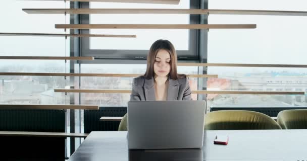 Занепокоєна жінка працює на портативному комп'ютері і дивиться в очі, думаючи вирішити проблему в офісі. Серйозна приваблива жінка, що працює з ноутбуком — стокове відео