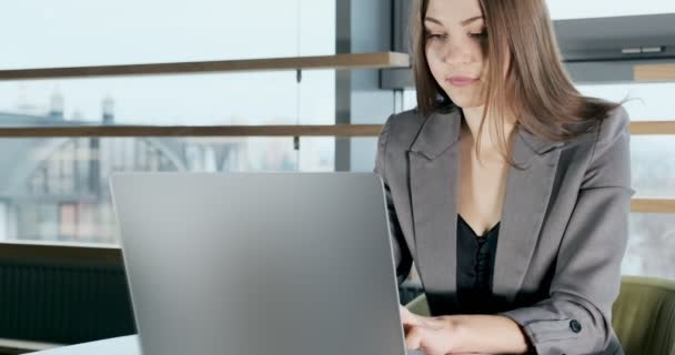 Concerned woman working on laptop computer and looking away thinking solving problem at office. Serious attractive female working with notebook — ストック動画