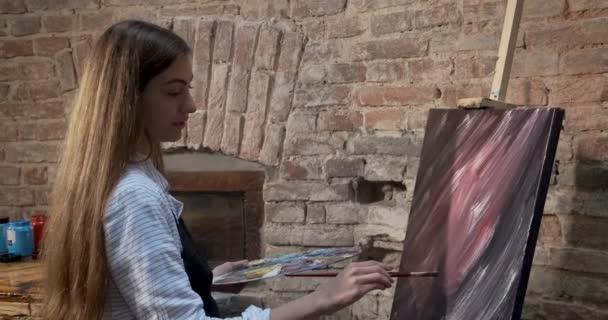 Talentoso inovador bonito Artista feminina desenha com escova na tela. Jovem pintora contemporânea criando quadro abstrato. Menina atraente cria pintura de arte moderna — Vídeo de Stock