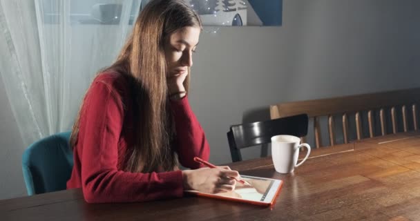 Талановита інноваційна красива жінка-дизайнер сидить і працює за столом. Сучасна молода жінка пише, малює і використовує ручку з цифровим планшетом. Приваблива дівчина створює цифрові ілюстрації — стокове відео