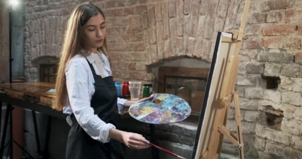 Talentovaný inovativní hezká žena umělec kreslí se štětcem na plátně. Současná mladá žena malířka vytváří abstraktní obraz. Atraktivní dívka vytváří moderní umění malířství — Stock video