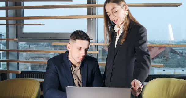Portrait of a man and a woman discussing work with notebook in the brightly lit modern office. Concerned female tell working male with laptop. Serious business people working with notebook — Stock Video