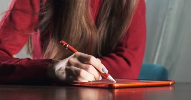 Feche o designer feminino sentado e trabalhando na mesa. Jovem contemporânea desenhando e usando caneta com comprimido digital. Menina atraente cria ilustrações digitais — Vídeo de Stock