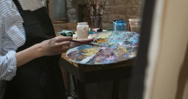 Närbild av kvinna hand blanda oljefärger på träpalett. Attraktiv flicka skapar modern konst målning. Närbild kvinnlig artist hand med pensel — Stockvideo