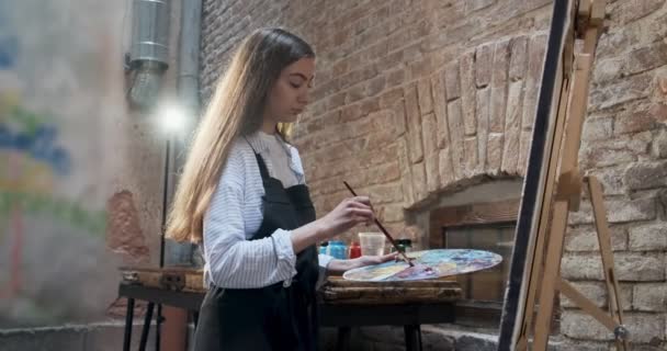 Yetenekli yenilikçi, güzel kadın sanatçı tuvalde fırçayla çizim yapıyor. Çağdaş genç kadın ressam soyut bir resim yaratıyor. Çekici kız modern resim yapıyor. — Stok video
