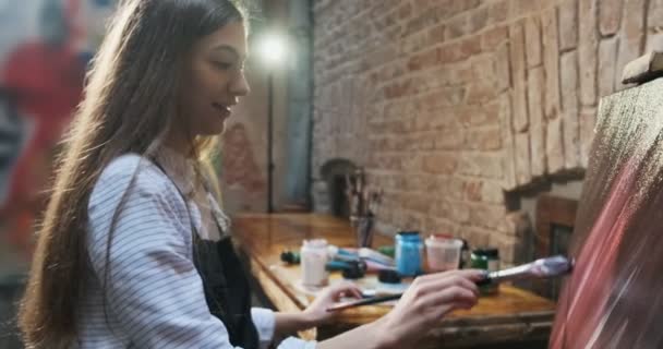 Yetenekli yenilikçi, güzel kadın sanatçı tuvalde fırçayla çizim yapıyor. Çağdaş genç kadın ressam soyut bir resim yaratıyor. Çekici kız modern resim yapıyor. — Stok video