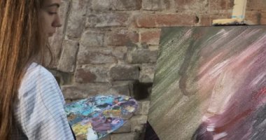 Yetenekli yenilikçi, güzel kadın sanatçı tuvalde fırçayla çizim yapıyor. Çağdaş genç kadın ressam soyut bir resim yaratıyor. Çekici kız modern resim yapıyor.