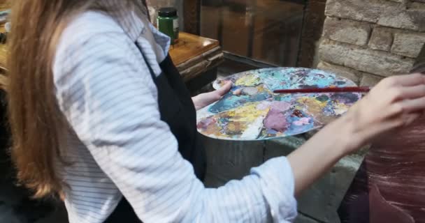 Close up of woman hand mixing oil paints on wooden palette. Attractive girl creates modern art painting. Close up female artist hand with paintbrush — 비디오