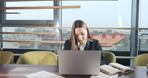 Mujer preocupada trabajando en el ordenador portátil y mirando hacia otro lado pensando en resolver el problema en la oficina. Femenina atractiva seria trabajando con cuaderno — Vídeo de stock