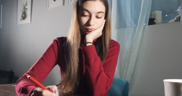 Masada oturan ve çalışan yenilikçi, güzel bayan tasarımcı. Çağdaş genç kadın dijital tabletle yazma, çizme ve kalem kullanıyor. Çekici kız dijital çizimler yapıyor — Stok video