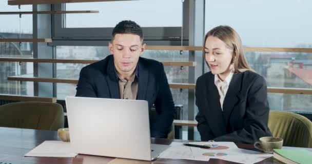 Homme et femme discutent du travail dans le bureau moderne très éclairé. Homme et femme concernés travaillant avec un ordinateur portable et donner cinq. Les gens d'affaires discutent du nouveau concept de projet de démarrage — Video