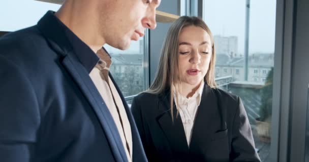 Man and a woman discussing work in the brightly lit modern office. Concerned male and female working with charts papers at hands. Standing business people discuss new startup project concept — 비디오