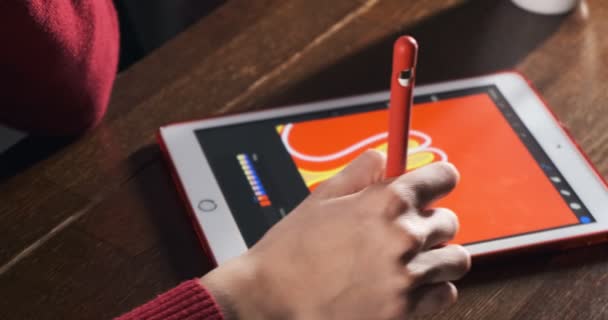 Primer plano diseñador femenino sentado y trabajando en el escritorio. Mujer joven contemporánea dibujando y usando pluma con tableta digital. Chica atractiva crea ilustraciones digitales — Vídeo de stock