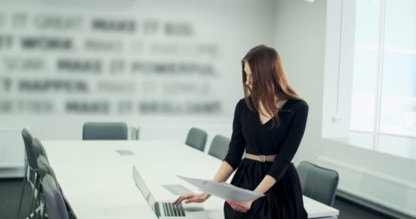 Sitting on table concerned woman working and thinking solving problem at office. Serious attractive female working with notebook and papers — Stock Video