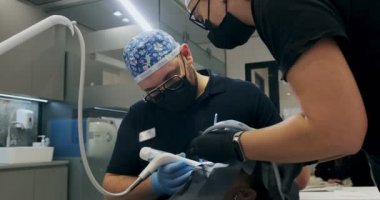 Ofiste çalışan erkek dişçiler. Bir dişçinin iki doktoru hava akışı diş temizliği yapıyor.