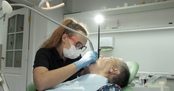 Dentista feminina fazendo tratamento odontológico para paciente idosa — Vídeo de Stock