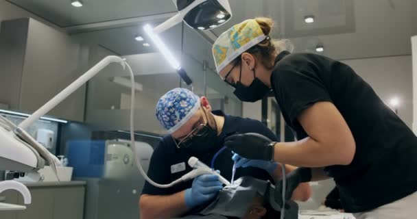 Odontólogos trabajando en la oficina. Dos doctores de un dentista hacen limpieza de dientes de flujo de aire — Vídeo de stock