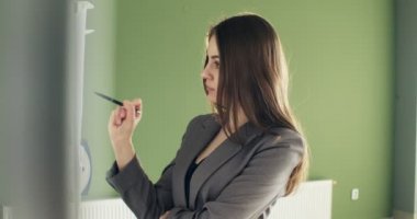 Güzel genç iş kadını sunum tahtasında finansal hesaplamalar yapıyor. Kadın kağıtlarıyla çalışıyor.