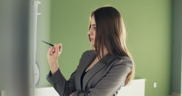 Mulher de negócios jovem bonita executa cálculos financeiros no quadro branco de apresentação. Trabalhando com papéis femininos — Vídeo de Stock