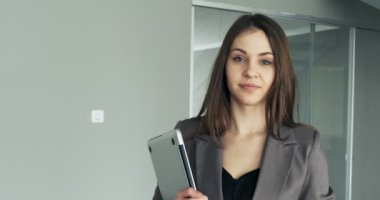 Ofis koridorunda yürüyen genç bir iş kadını. Ciddi çekici bir kadın defter ve kağıtlarla konferansa gidiyor.