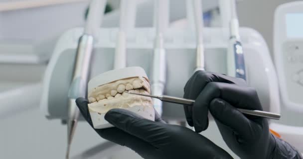 Dentista muestra al paciente en el modelo de la mandíbula cómo tratar adecuadamente sus dientes, el cuidado de los dientes y la cavidad oral — Vídeos de Stock