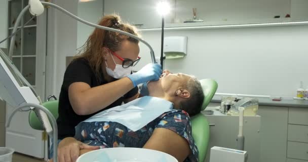 Vrouwelijke tandarts doet tandheelkundige behandeling bij oudere vrouw patiënt — Stockvideo