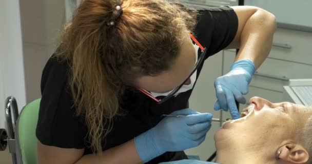 Женщина-дантист делает стоматологическое лечение пожилой пациентке — стоковое видео