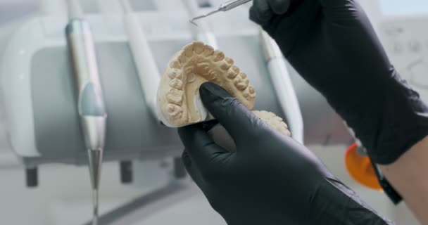 Dentista muestra al paciente en el modelo de la mandíbula cómo tratar adecuadamente sus dientes, el cuidado de los dientes y la cavidad oral — Vídeos de Stock