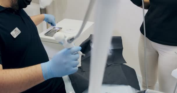 Odontólogos trabajando en la oficina. Dos doctores de un dentista hacen limpieza de dientes de flujo de aire — Vídeo de stock