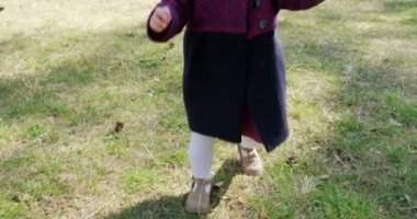 Kozalaklı ormandaki ağaçların arasında yeşil çimenlerde yürüyen mutlu küçük kız. Sosyal izolasyonda sağlıklı çocuk eğlencesi. Bahar ormanı güzelliği