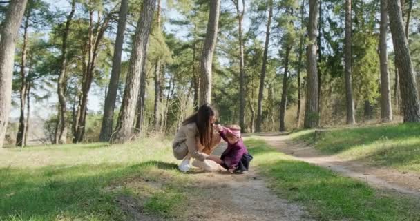 Szczęśliwa dziewczynka spacerująca i bawiąca się z matką wśród drzew w lesie iglastym. Zdrowe dziecko rekreacji rodzinnej w izolacji społecznej. Wiosenne piękno lasu — Wideo stockowe