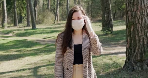 Retrato de una joven con máscara protectora en el bosque de coníferas. Protección, covid-19, coronavirus, virus, pandemia, aislamiento social — Vídeo de stock