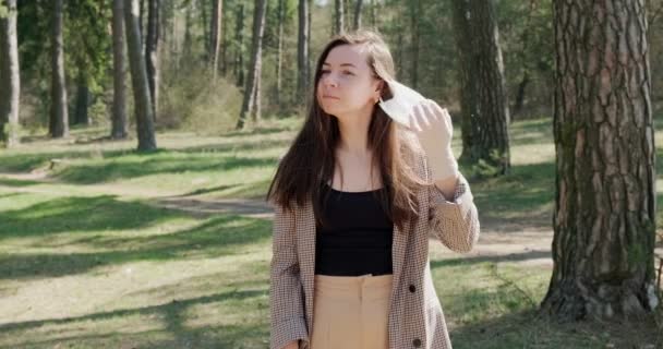 Retrato de uma jovem mulher adiar máscara protetora na floresta de coníferas. Proteção, covid-19, coronavírus, vírus, pandemia, isolamento social — Vídeo de Stock